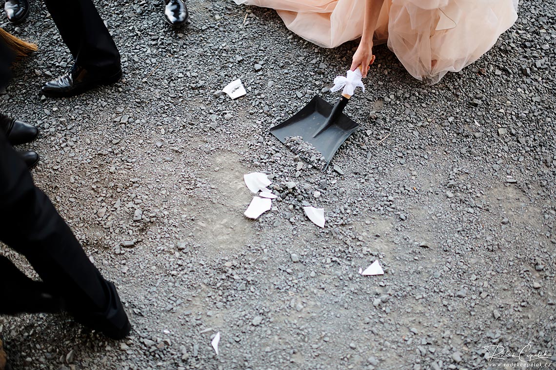 bride and groom cleaning the shards from broken plate