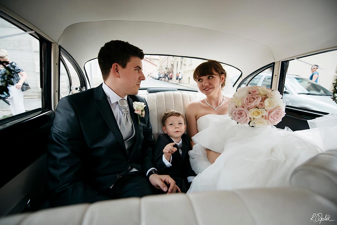 moment of smiling bride sitting into the vintage car