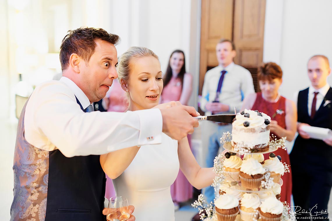 funny groom expresion during cutting the wedding cake