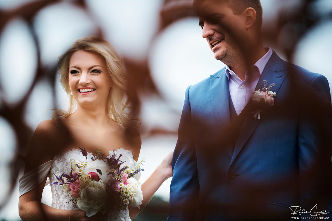 Smiling bride and groom during outside wedding ceremony.