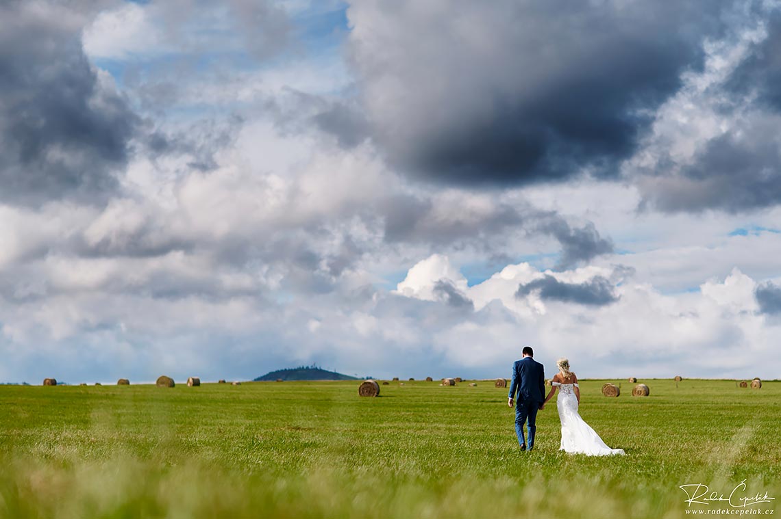 Bride and groom walking on the field with grass