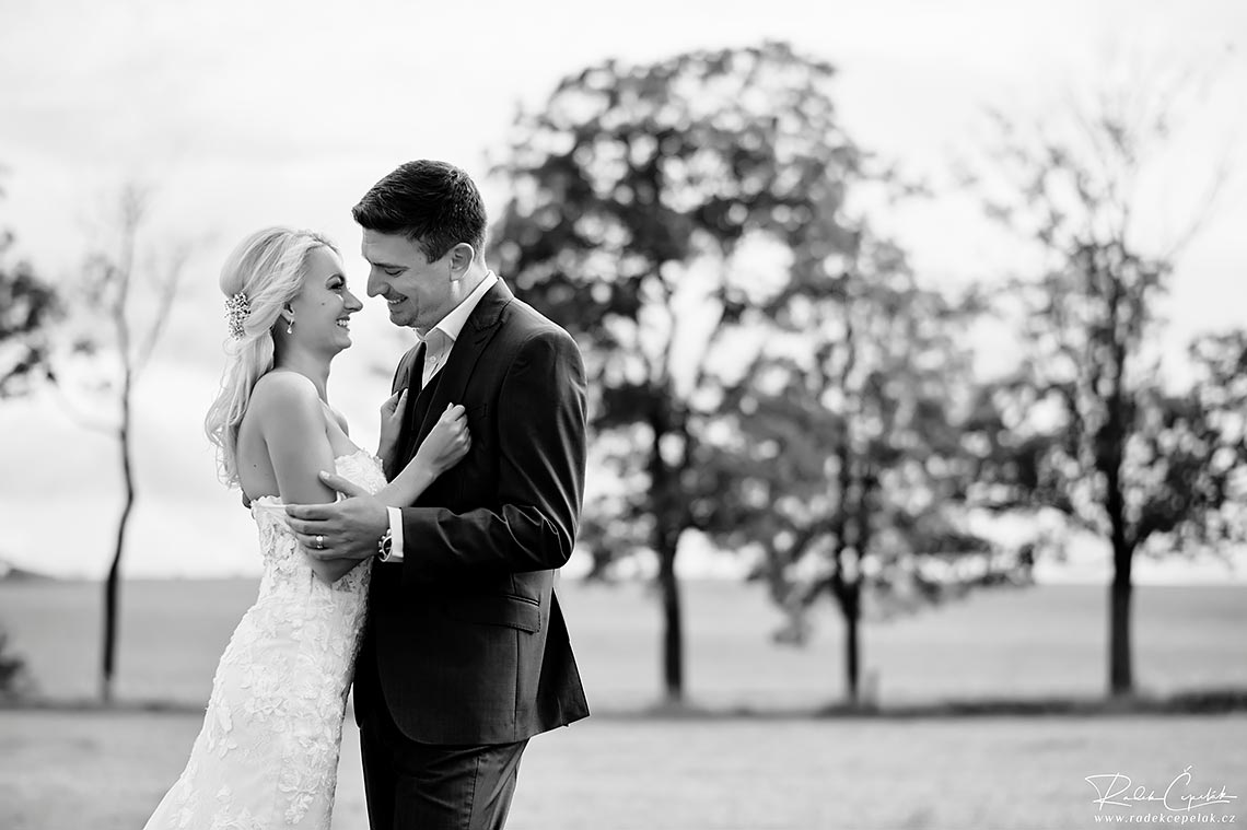 Black and white wedding photography of bride and groom with trees in the background