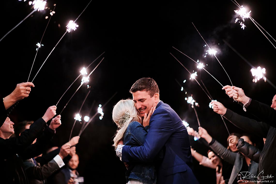 Sweet groom expression hugging bride under sparkles